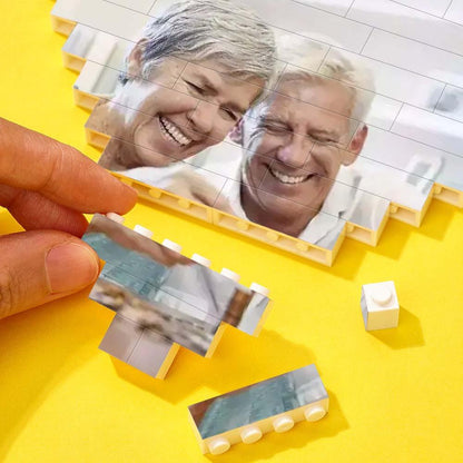 Assembling personalized heart-shaped photo block puzzle with elderly couple, DIY gift, interlocking bricks, vibrant colors.
